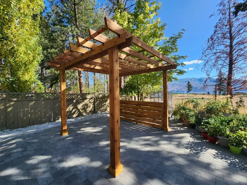 Pergola on a stone floor with trees in the background made by sweet yards in Kelowna
