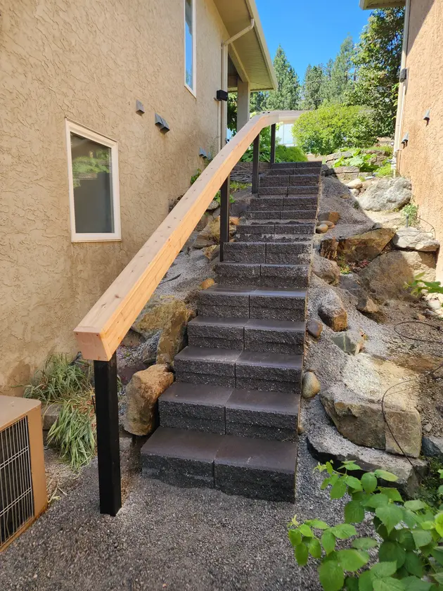 Stone stairs with a wooden hand rail done by sweet yards in Kelowna